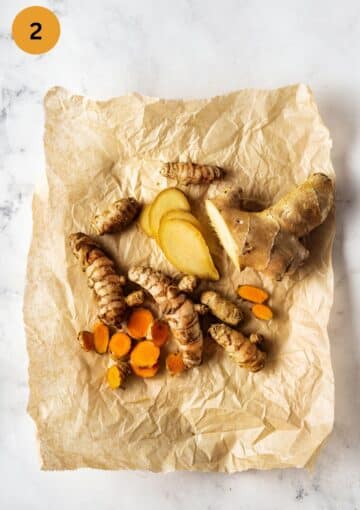 sliced fresh turmeric and ginger on a piece of parchment paper.