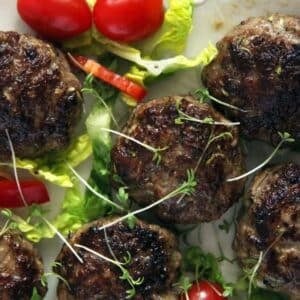 juicy zucchini meatballs with salad leaves and small tomatoes on the side.