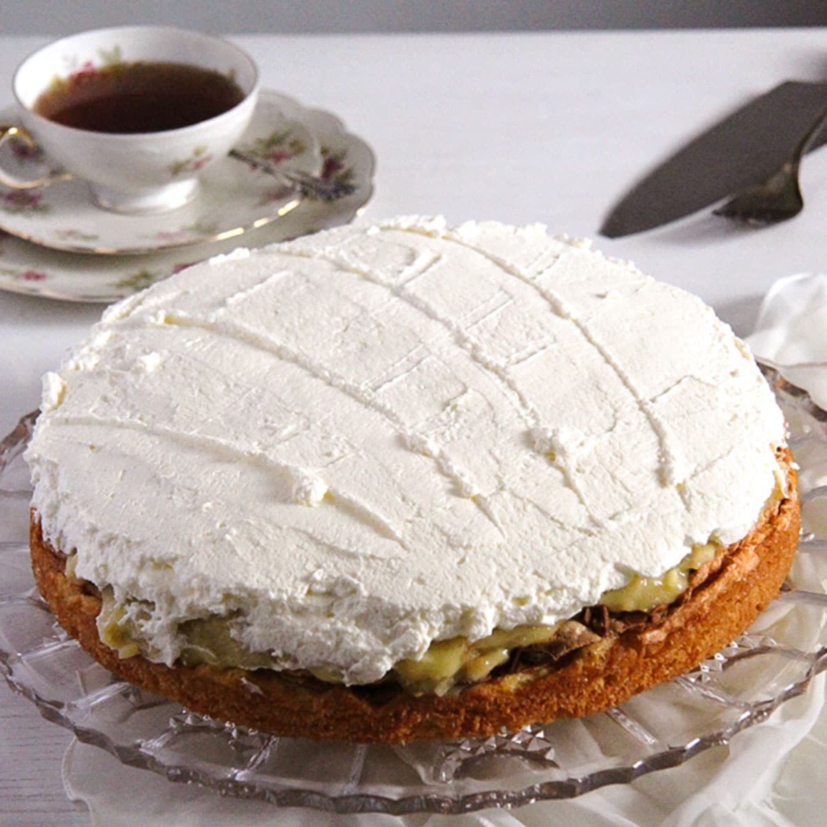 german apple cake covered with whipped cream on a cake platter.