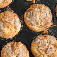 six golden brown muffins sprinkled with sugar in a tin.