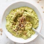 spicy avocado spread for bread sprinkled with sunflower seeds and spices in a bowl.