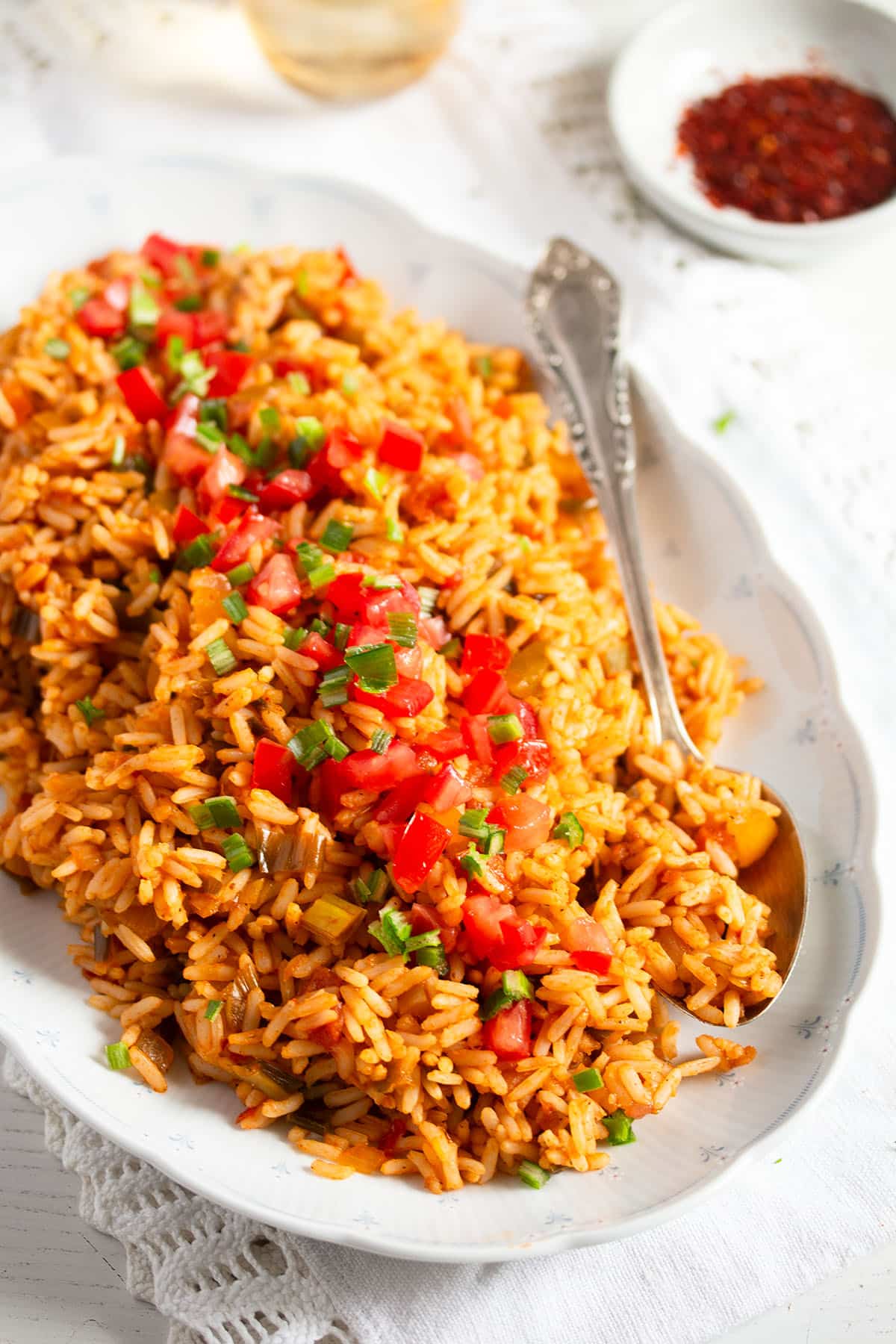 barbecue rice with tomatoes, peppers and parsley on a platter with a spoon.