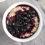 buckwheat porridge topped with bluebbery compote in a small bowl.