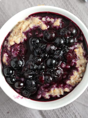 buckwheat porridge topped with bluebbery compote in a small bowl.