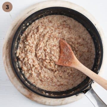 stirring creamy porridge made with buckwheat groats in a saucepan with a wooden spoon.