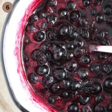 stirring blueberry sauce with a spoon in a saucepan.