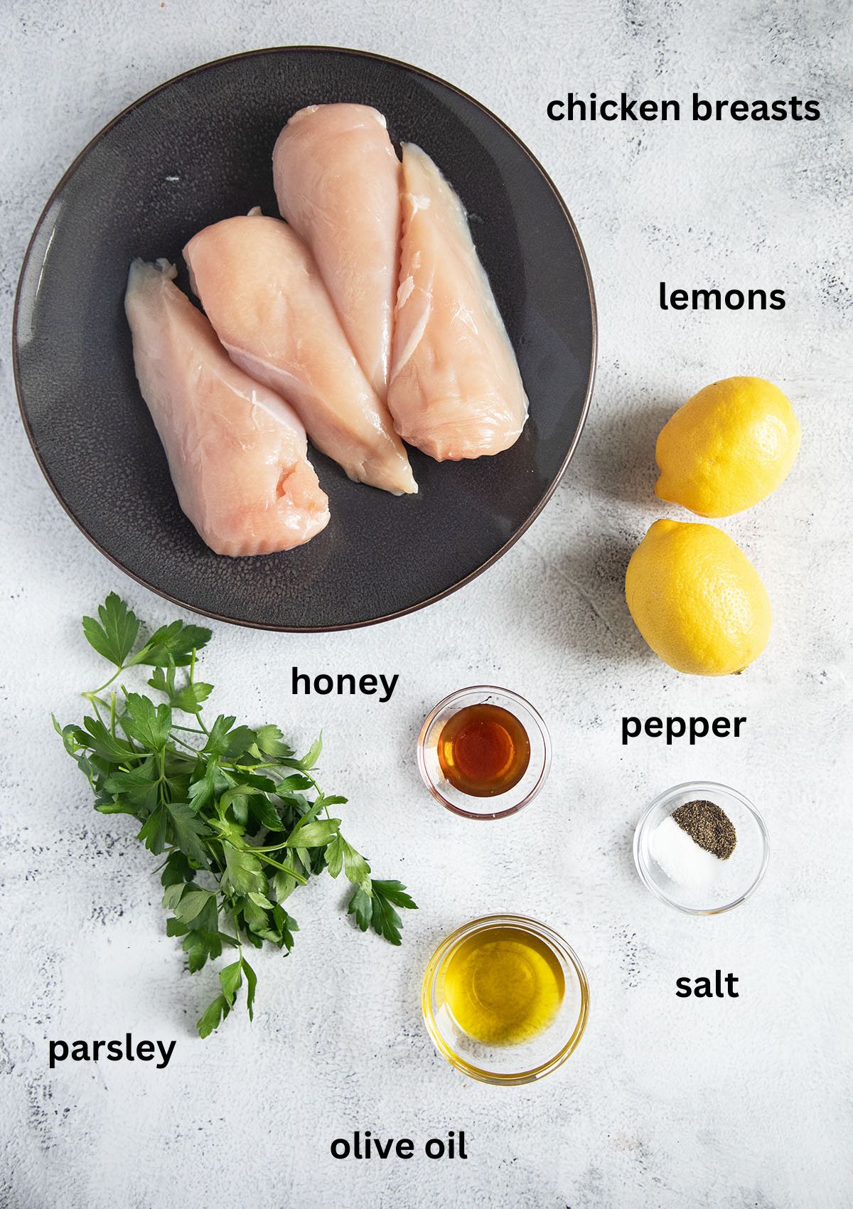 ingredients for cooking chicken breasts with parsley, lemons, honey and olive oil.