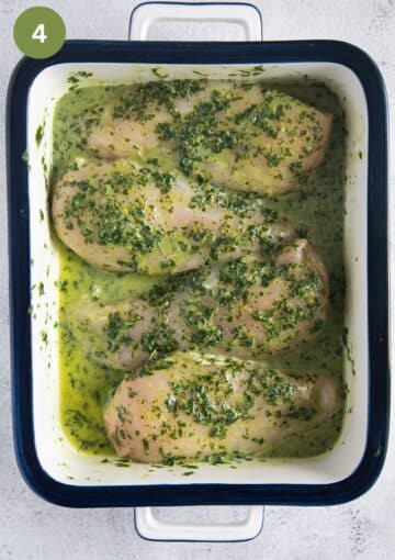 four chicken breasts covered with herb and lemon marinade in a small casserole dish