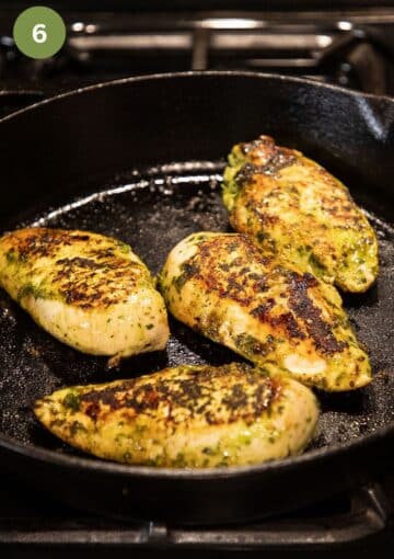 four chicken breasts searing in a skillet.