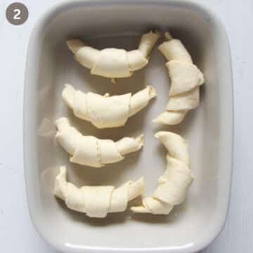 five rolled crescent rolls in a baking dish before baking.