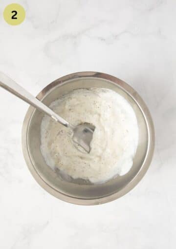 sour cream mixture for coleslaw in a bowl with a spoon in it.