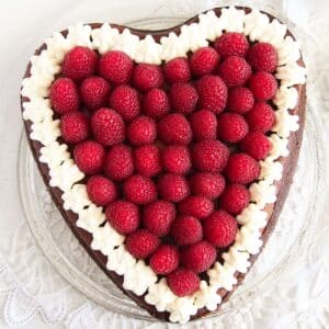 heart shaped cheesecake topped with fresh raspberries and cream.