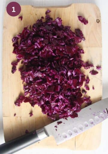 chopped red cabbage and a chef's knife on a cutting board.