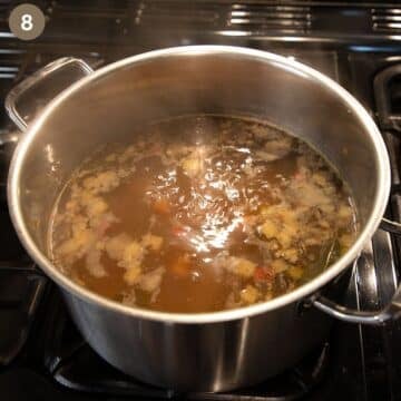 simmering bone broth soup with vegetables on the stovetop.