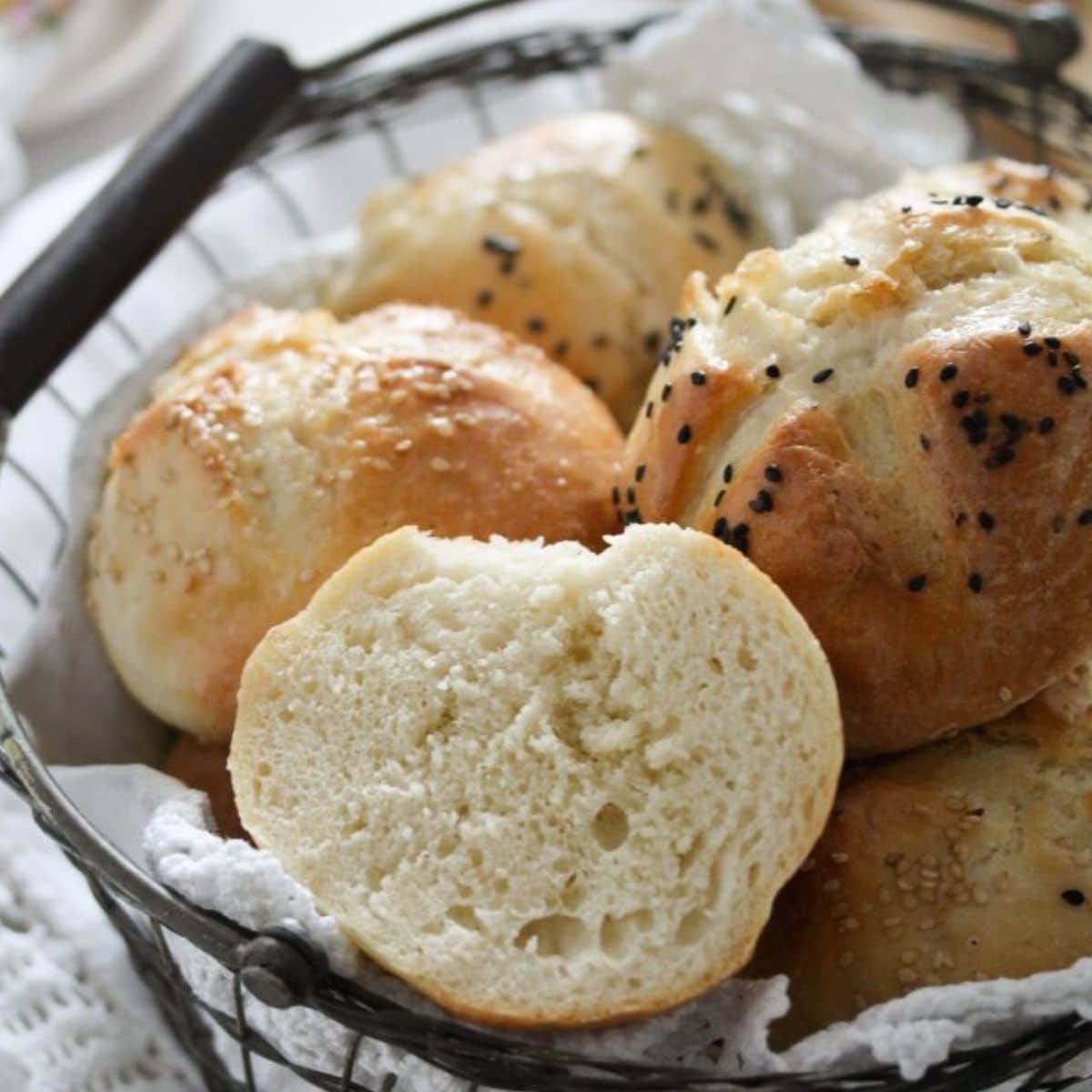 breakfast bread rolls in a bread basket, one split to show the crumb.