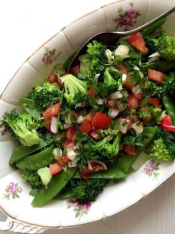 broccoli pea salad with tomato pieces on a vintage platter.