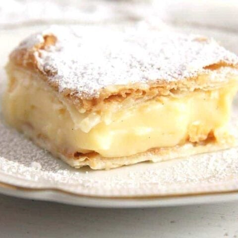 cremeschnitte piece sprinkled with icing sugar on a plate