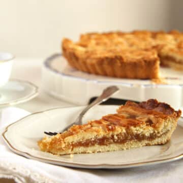 a slice of harry potter's treacle tart and the rest of the tart on a platter behind.