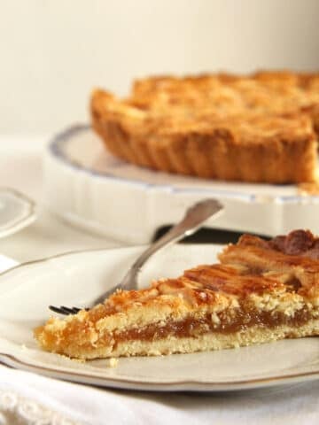 a slice of harry potter's treacle tart and the rest of the tart on a platter behind.