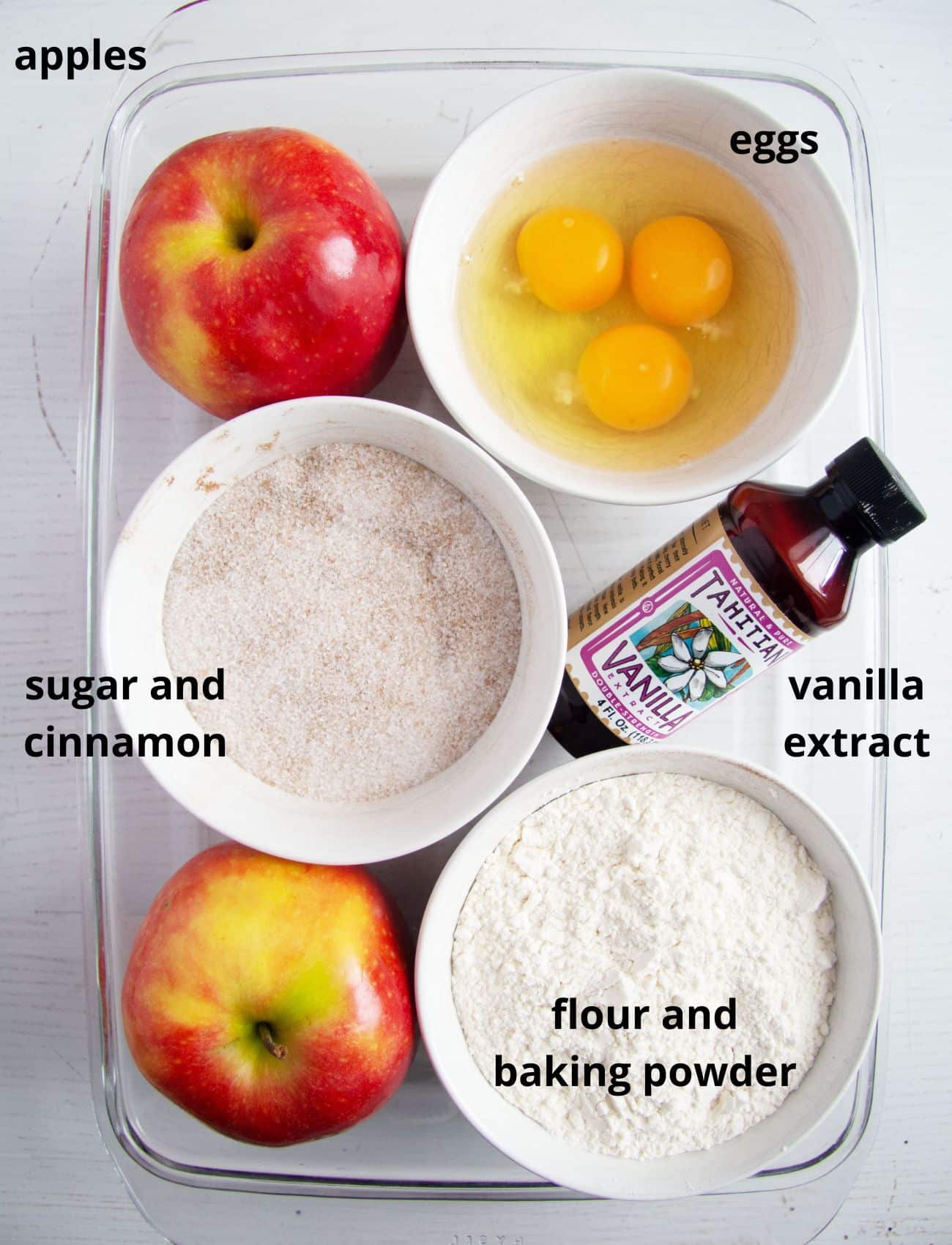 apples, eggs, sugar, flour and vanilla extract in bowls.
