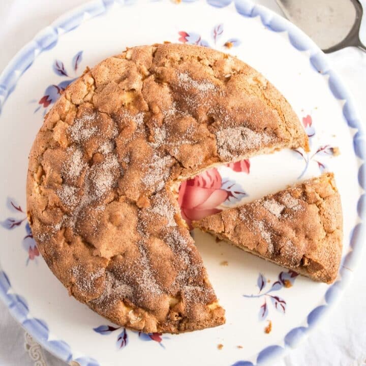 overhead view of a sliced healthy apple cake on a vintage platter with blue pattern.