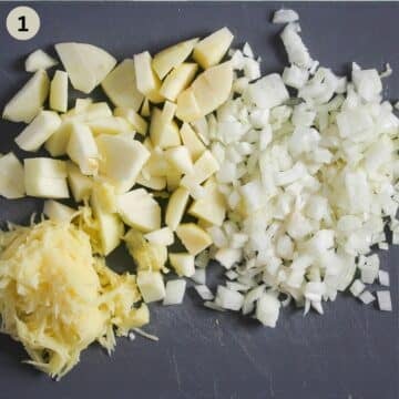 chopped apples and onions and grated potatoes on a cutting board for cooking sauerkraut with them.