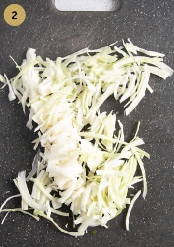 thinly sliced white cabbage on a cutting board.