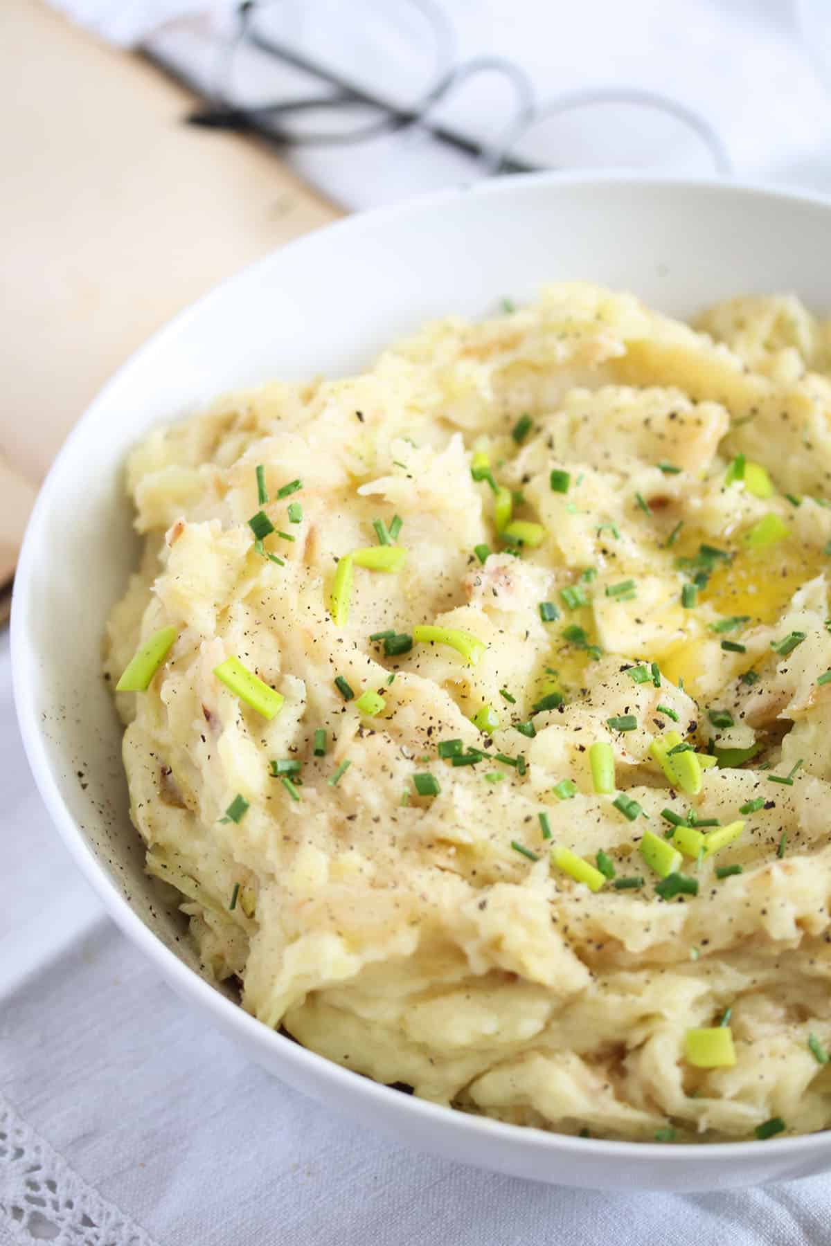 mashed potatoes with cabbage in a large bowl and a pair of glassees behind it.