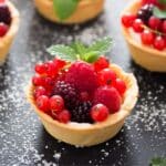 mini fruit tart filled with fresh red berries and garnished with mint leaves.