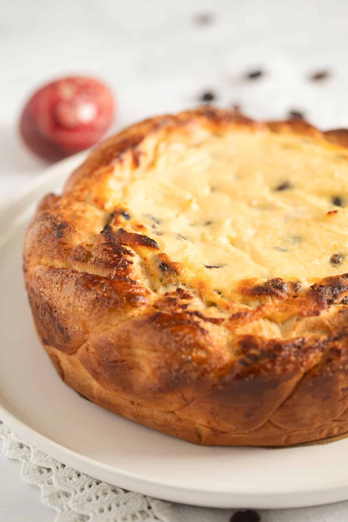 golden Pasca cheesecake baked on a platter with an easter egg behind it.