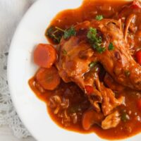 white plate full of stew with rabbit meat and veggies.