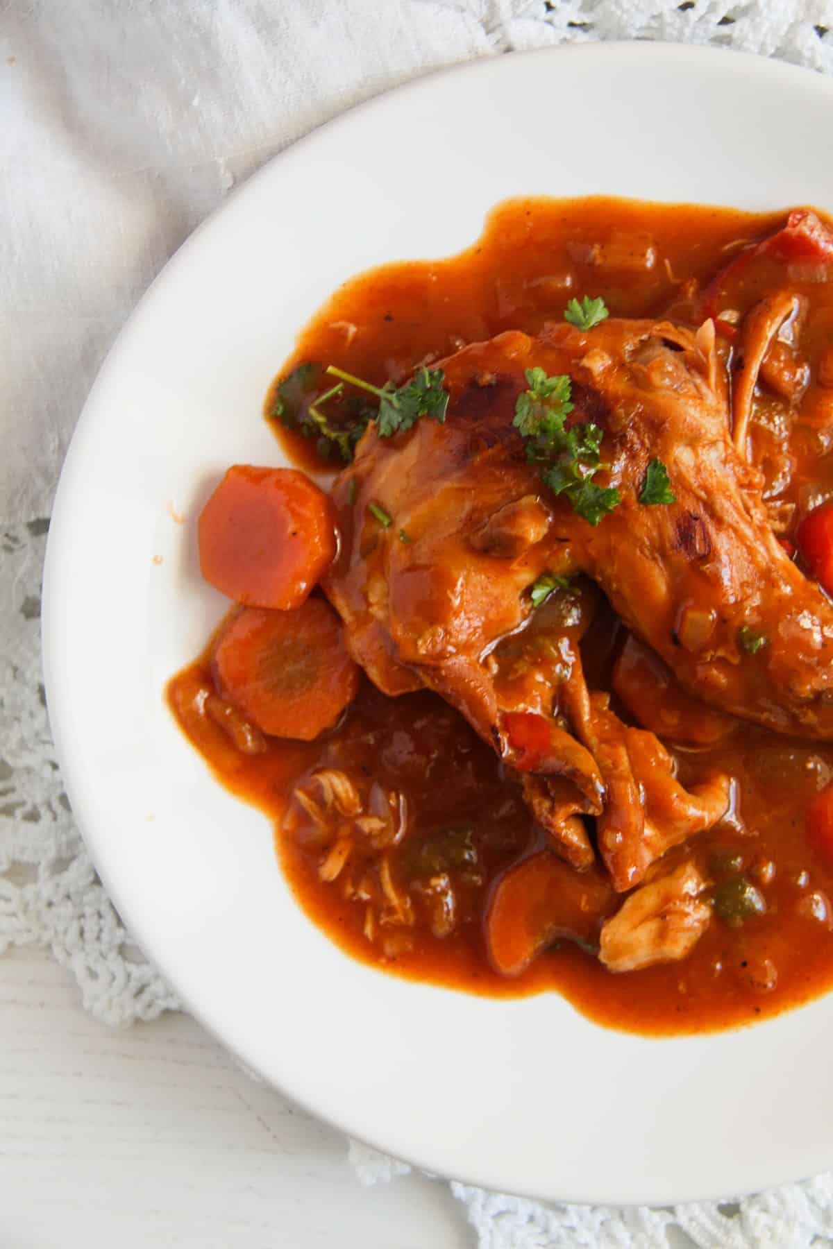 white plate full of stew with rabbit meat and veggies.