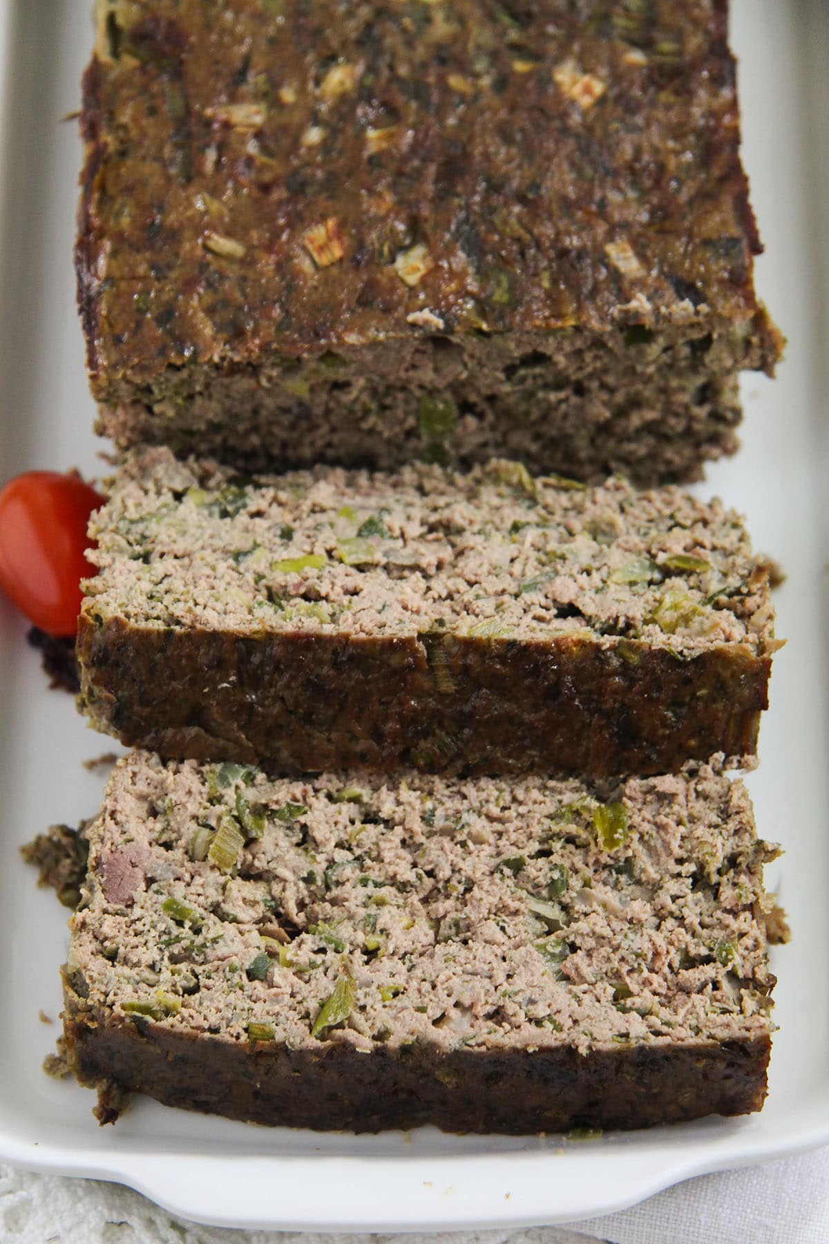 sliced drob with green onions, chicken and herbs on a platter.