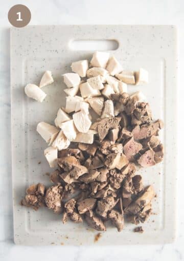 roughly chopped cooked chicken breast and chicken livers on a cutting board.