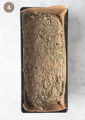 unbaked romanian drob with chicken and herbs in a loaf pan lined with parchment paper.