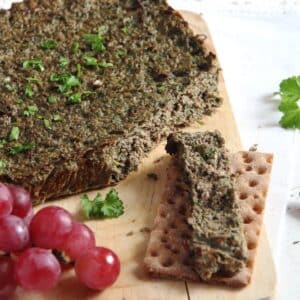 romanian easter drob served with with crispbread and red grapes on a cutting board.