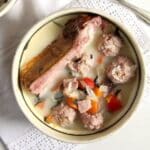 romanian meatball soup with a large pork rib in it in a traditional bowl.