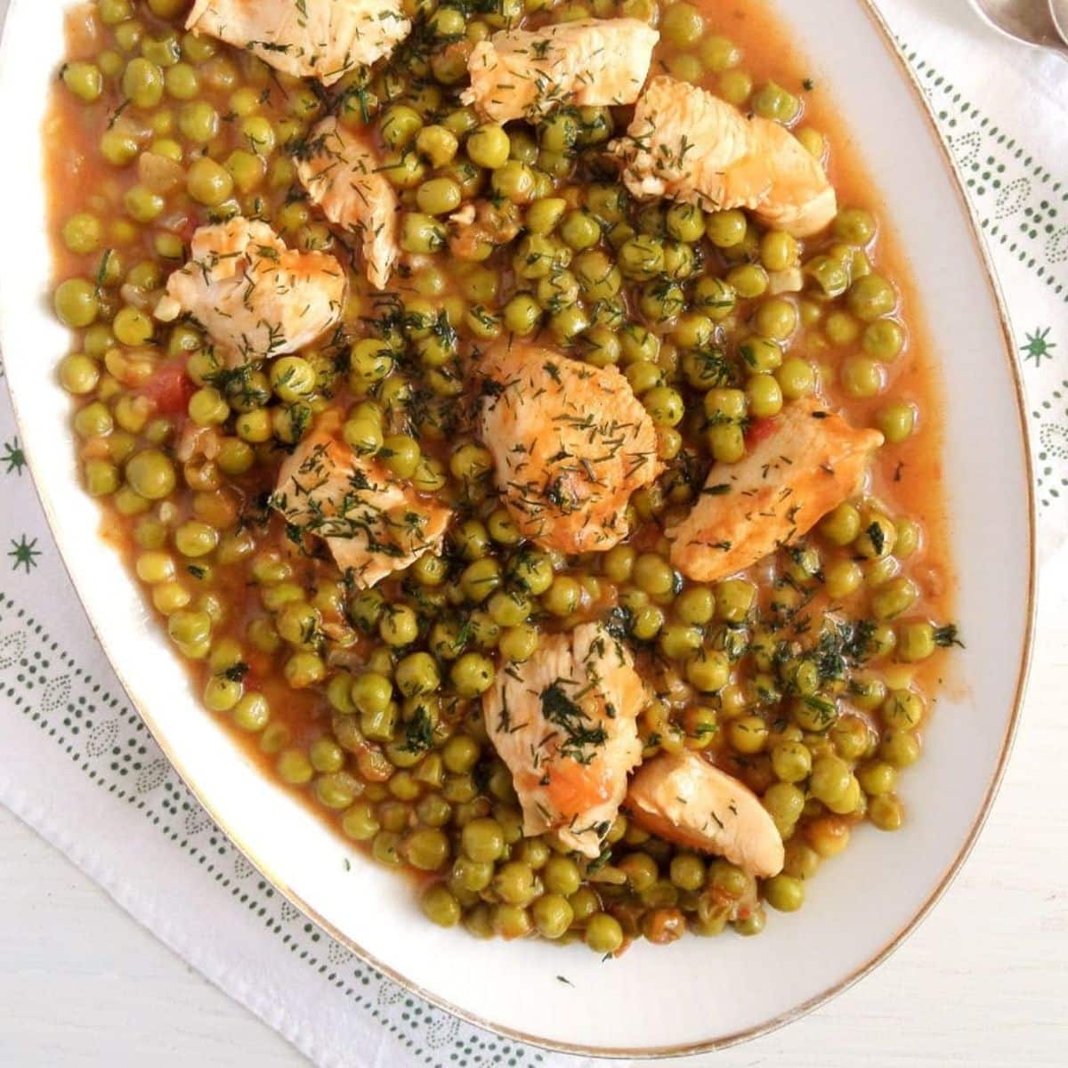 romanian chicken and pea stew sprinkled with dill on a large platter.