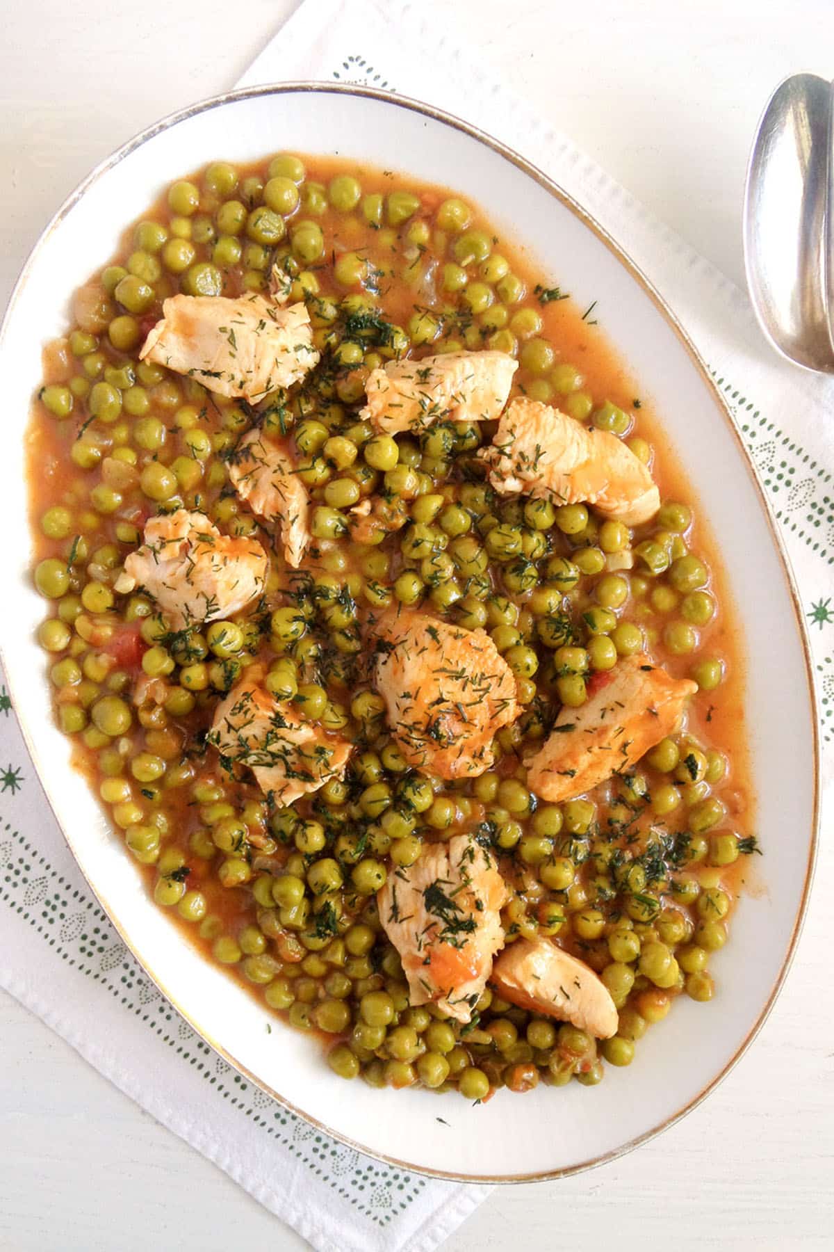 a platter full of romanian pea stew with chicken pieces on top.