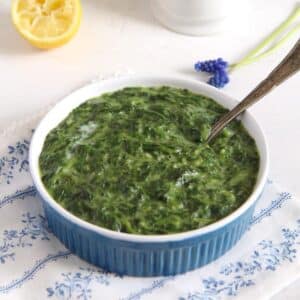 creamy spinach bechamel in a small blue bowl with a spoon in it.