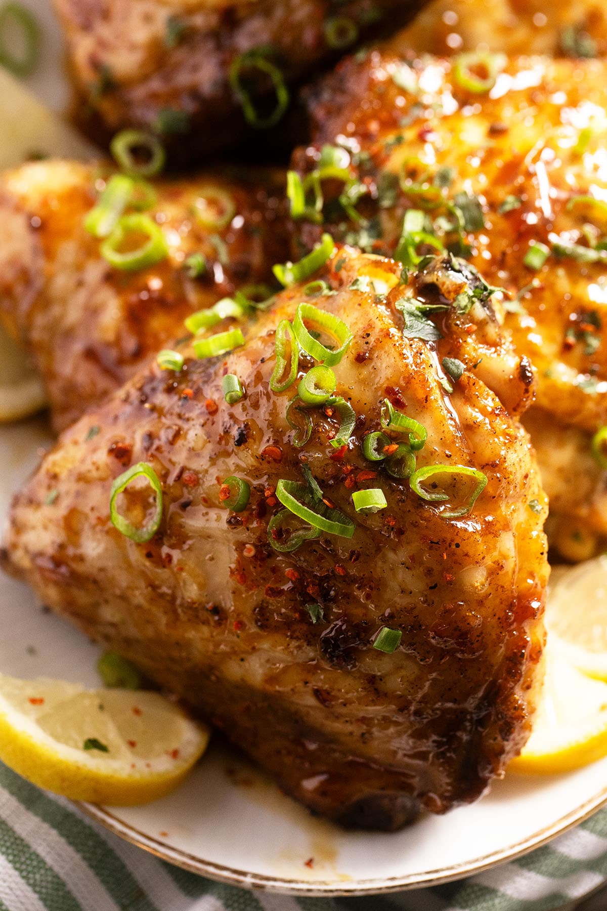 close up of one baked chicken thigh covered with sauce. 