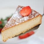 slice of two ingredient cake made with marzipan and eggs on a cake lifter with a strawberry slice on top.