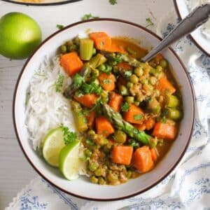 asparagus coconut curry served with lime wedges in a bowl.
