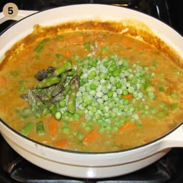 adding asparagus tips and frozen peas to a pot of curry.
