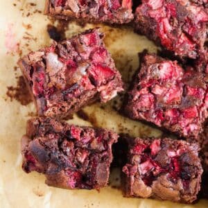 many brownies with strawberries on parchment paper.