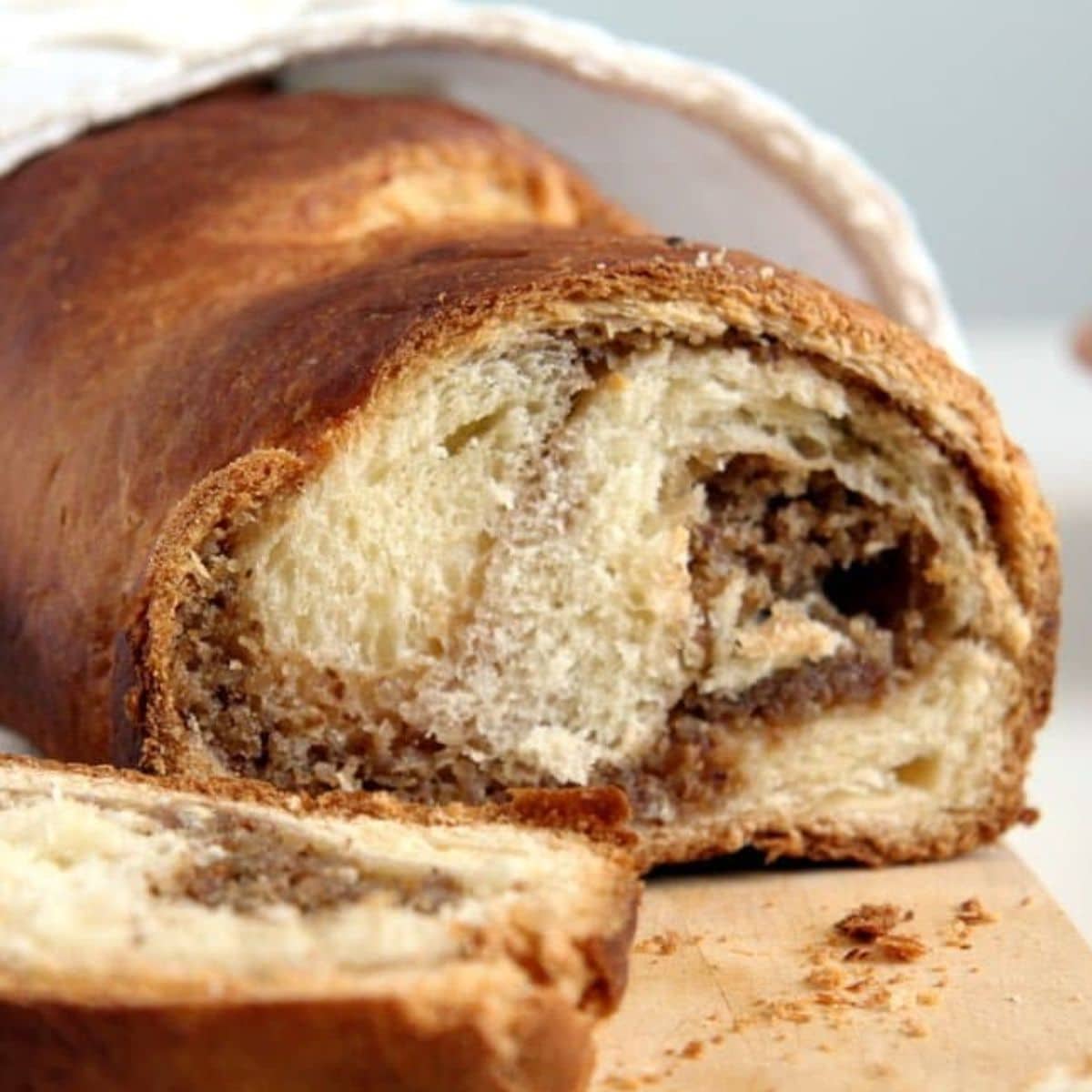 romanian cozonac sweet bread wrapped in a kitchen towel and a slice before it.