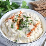 cream cheese egg salad sprinkled with paprika and chives in a bowl.