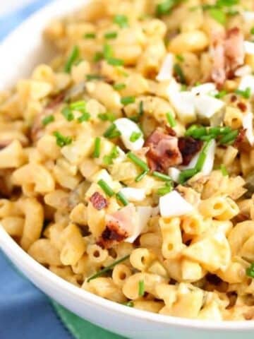 a bowl with creamy deviled egg pasta salad sprinkled with chives.