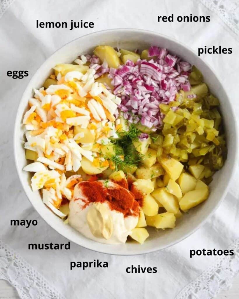 a bowl with chopped ingredients for deviled egg potato salad with text around the bowl.