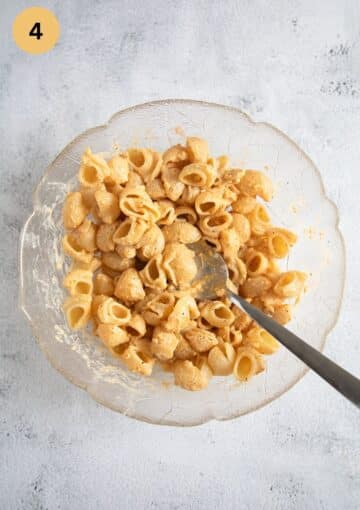 mixing macaroni with mayonnaise dressing in a bowl.
